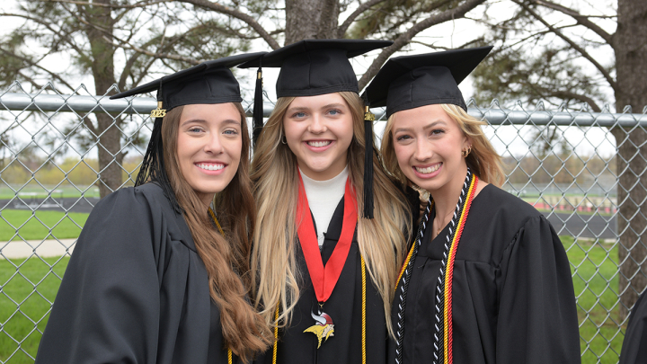 Three female graduates smiling for the camera on commencement day at Valley City State University